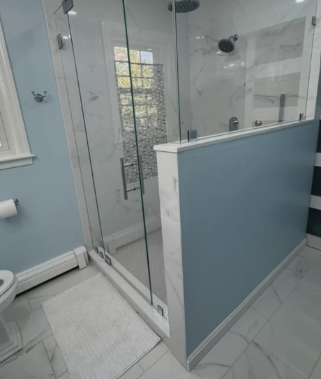 Walk-in shower with a blue half-wall and marble tile