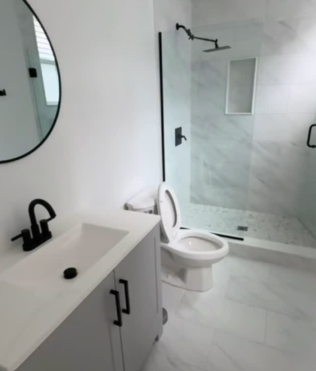 Bathroom with gray vanity, round mirror, and matte black fixtures