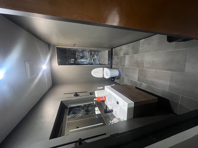 Office bathroom with a white vanity, dark tile, and black fixtures