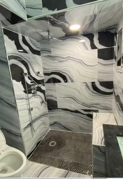 Custom marble tile shower with glass enclosure and hex tile floor